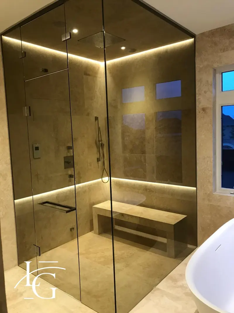 Bronze-tinted glass shower with LED-lit travertine