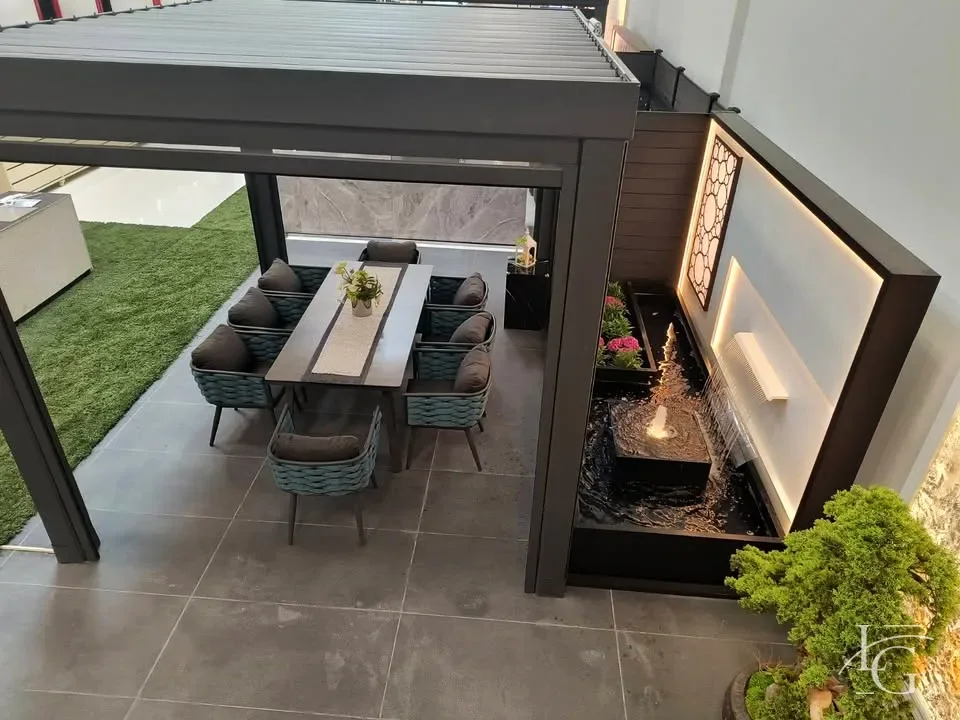 Louvered pergola over an outdoor dining table enclosed by glass walls