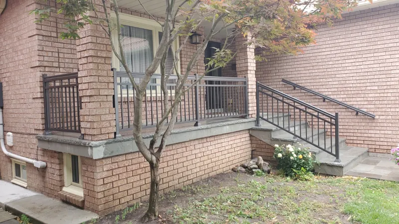 Black aluminum picket railing on a raised brick porch and side stair