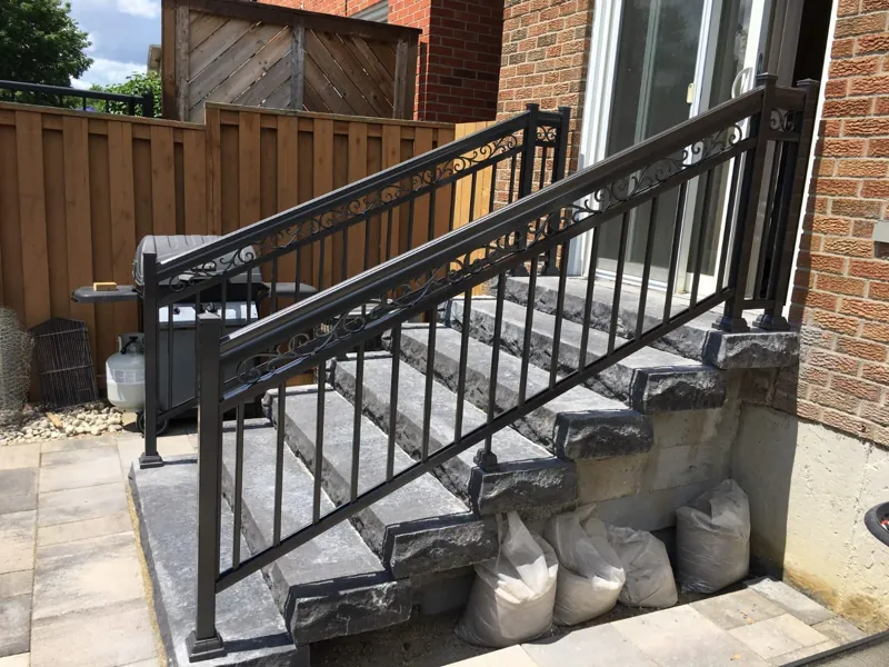 Black aluminum scroll railing, model R4, on concrete side steps