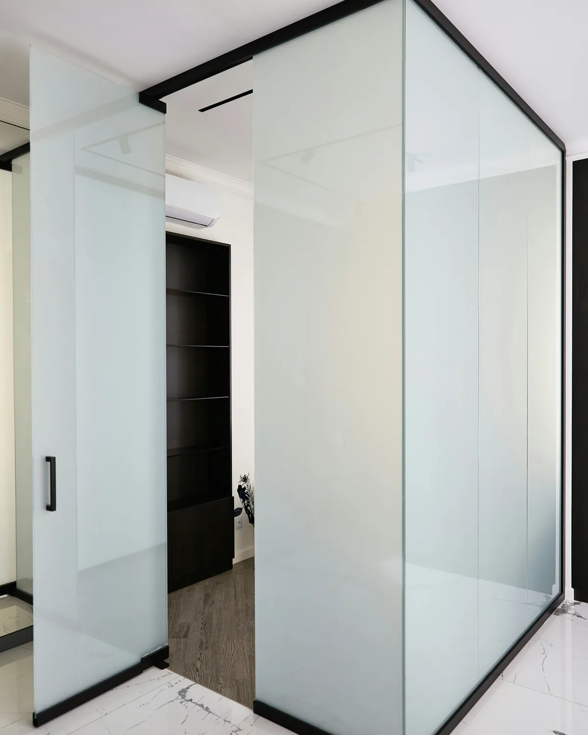 Glass room with a black frame and an open door, shown in the frosted private state