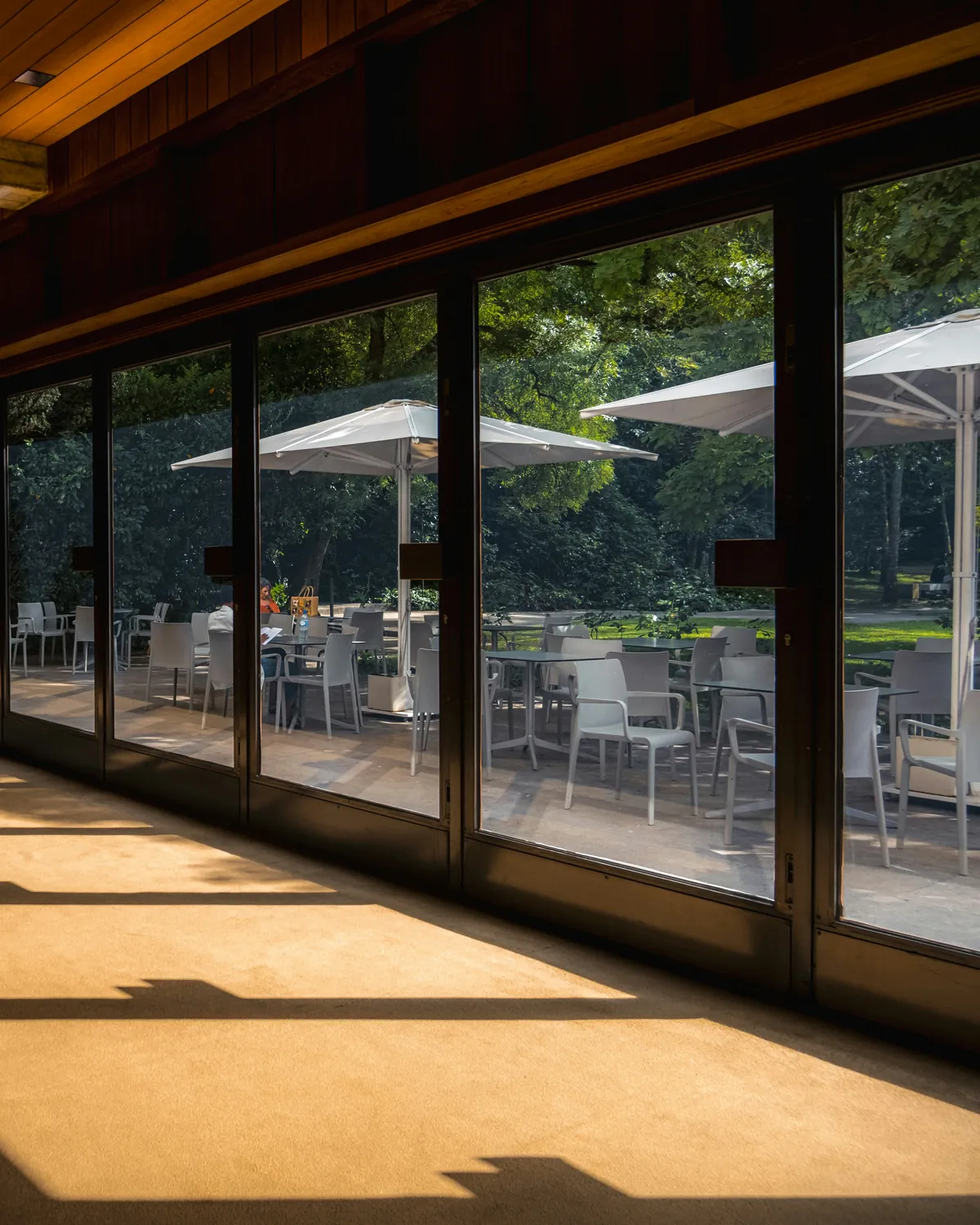 Row of tall multi-panel glass sliding doors along a sunlit hall